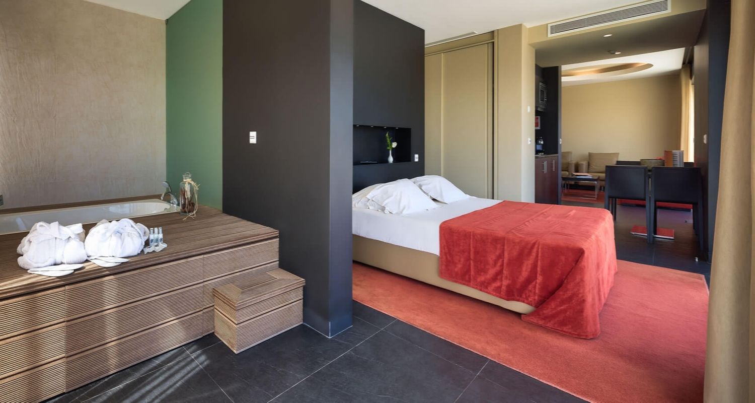 spacious hotel room with a double bed and red sheets