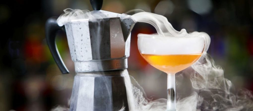 cocktail being poured from metal kettle with dry ice used as an ingredient