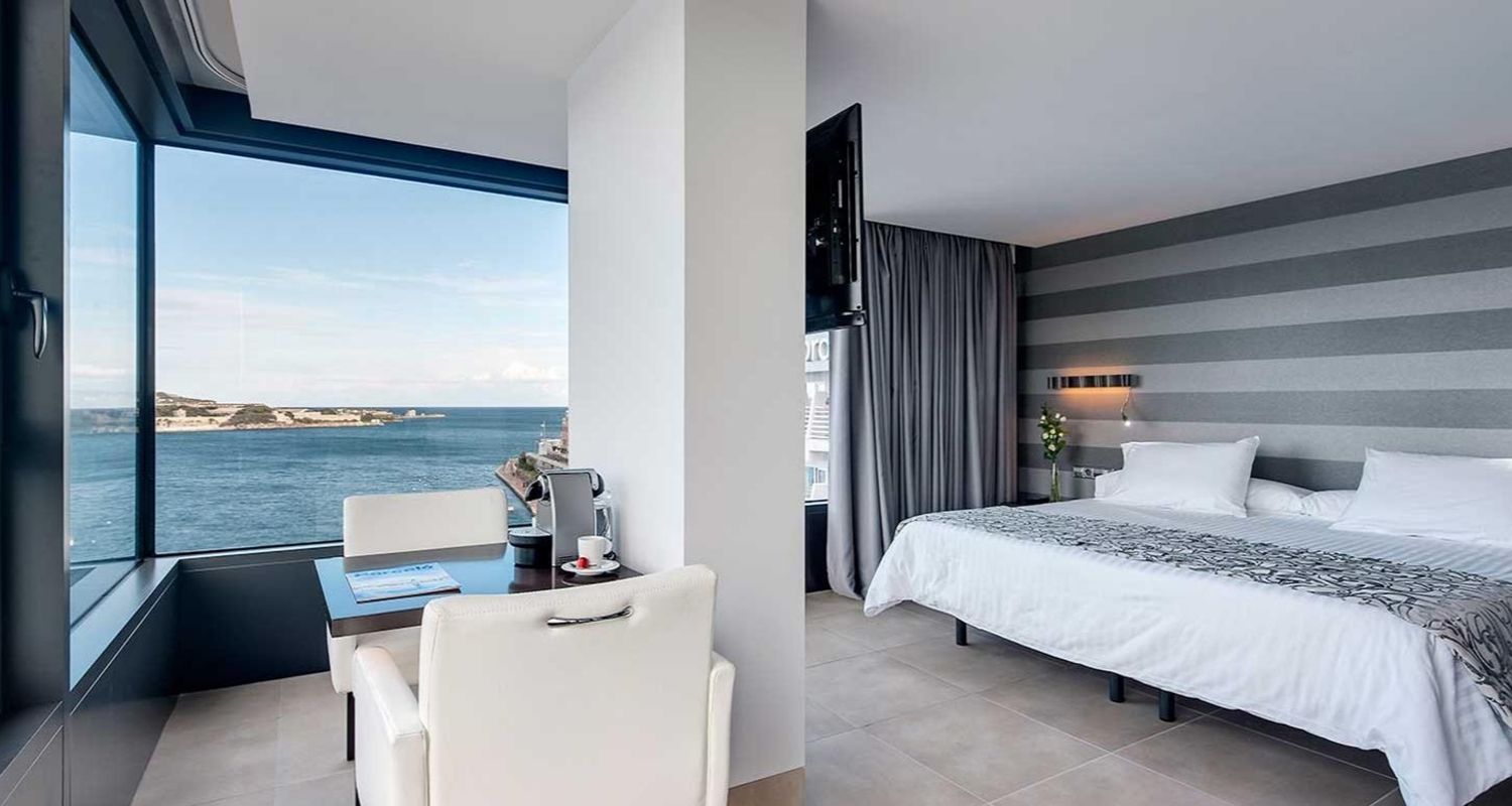spacious hotel suite with massive bed, flat screen tv and sea view