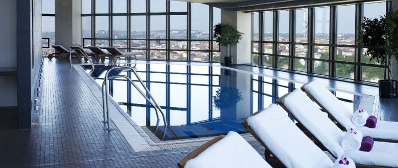 view of the sunbeds, indoor pool and the city