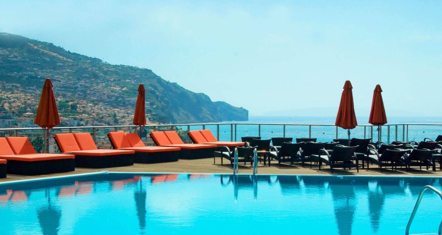 outdoor swimming pool with orange sunbeds and umbrellas