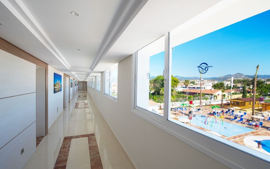 hallway leading to hotel rooms with a view of the outdoor swimming pool