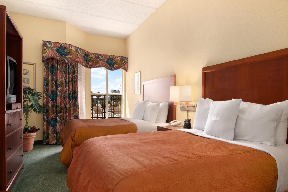 Spacious bedroom with twin double beds and a view of the pool