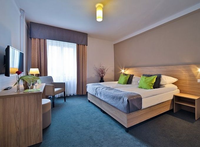 spacious bedroom with a queen sized bed and a flat screen tv