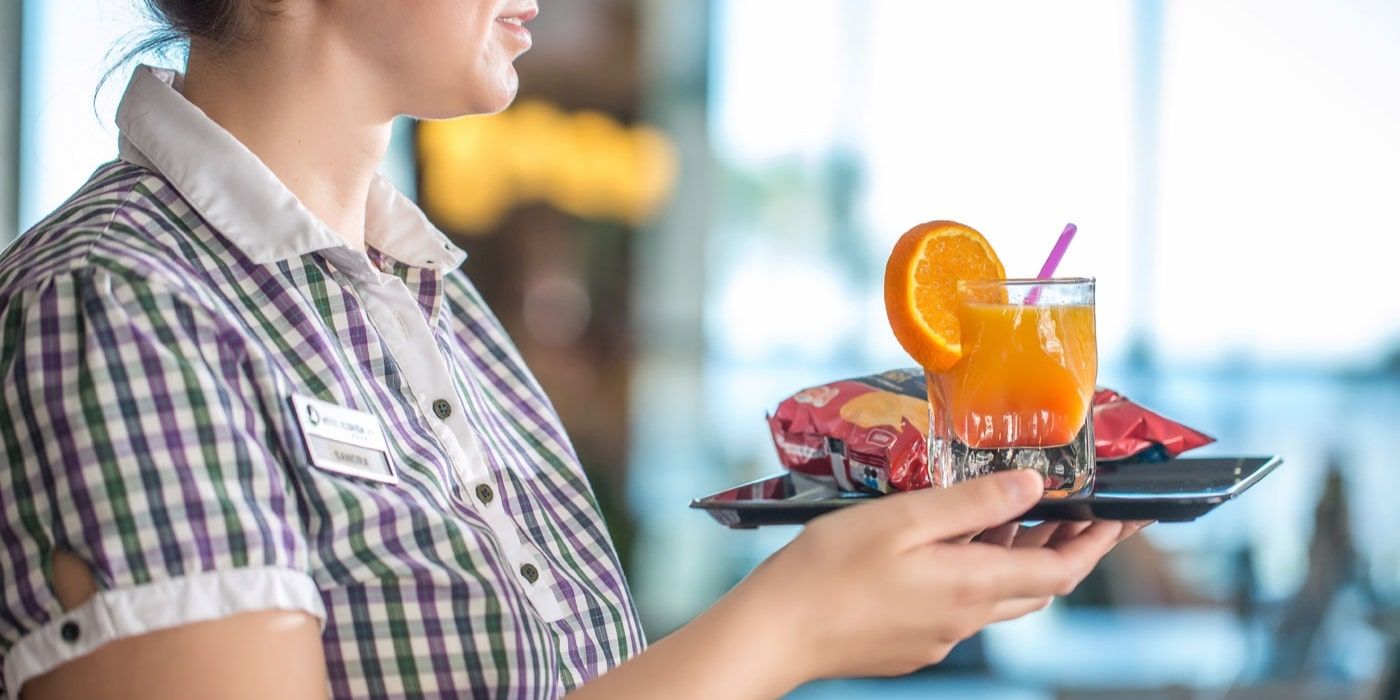 friendly hotel waitress delivering orange cocktail