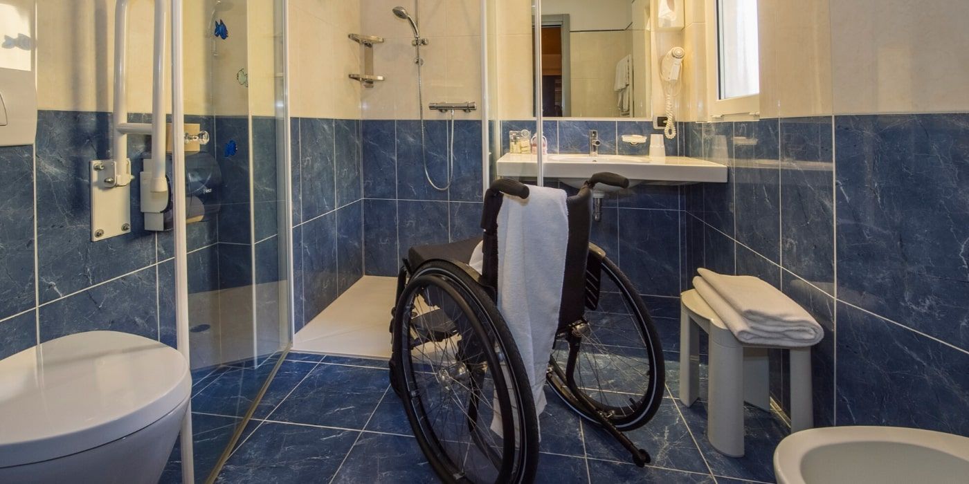 Adapted bathroom with a wheel-in shower, shower chair and grab rails at Hotel Kriss.