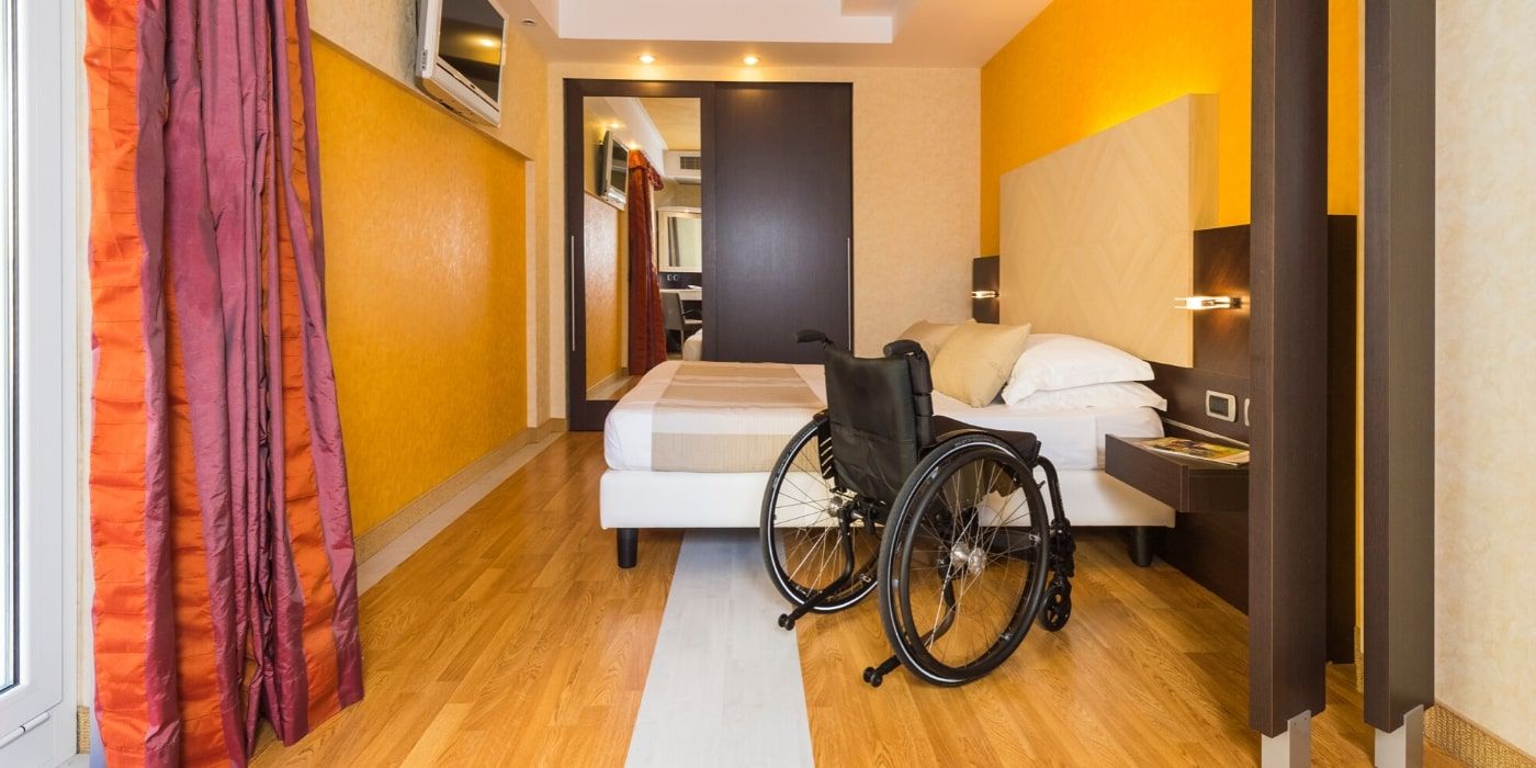 Wheelchair next to a bed in the accessible room at Hotel Kriss