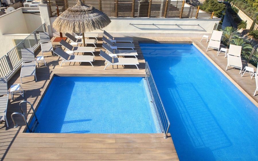 outdoor rooftop swimming pool with sunbeds surrounding it