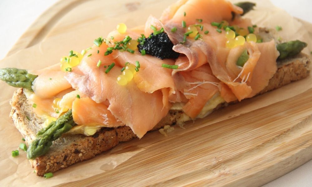 ham, asparagus and caviar sitting on a slice of toast 