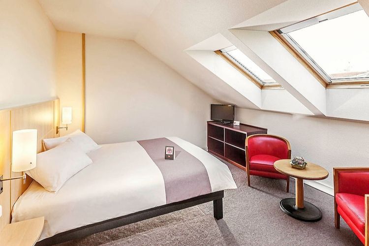 spacious bedroom with soft red chairs to sit on