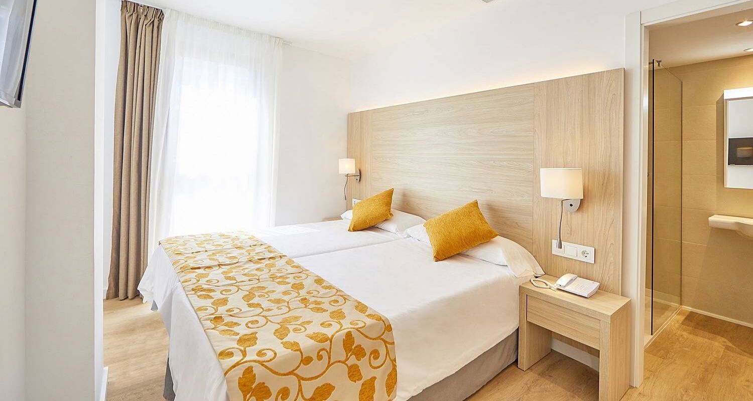 twin beds pushed together in a spacious bedroom leading toward the bathroom 