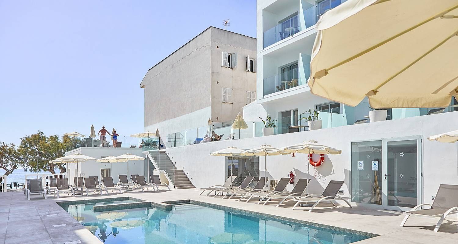hotel exterior and outdoor swimming pool surrounded by sunbeds