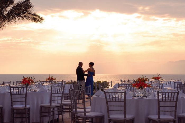 couple standing among wedding tables at sunset