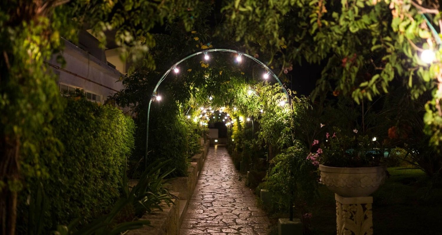 Flat pathway leading under an archway with twinkling lights - Muthu Clube Praia da Oura