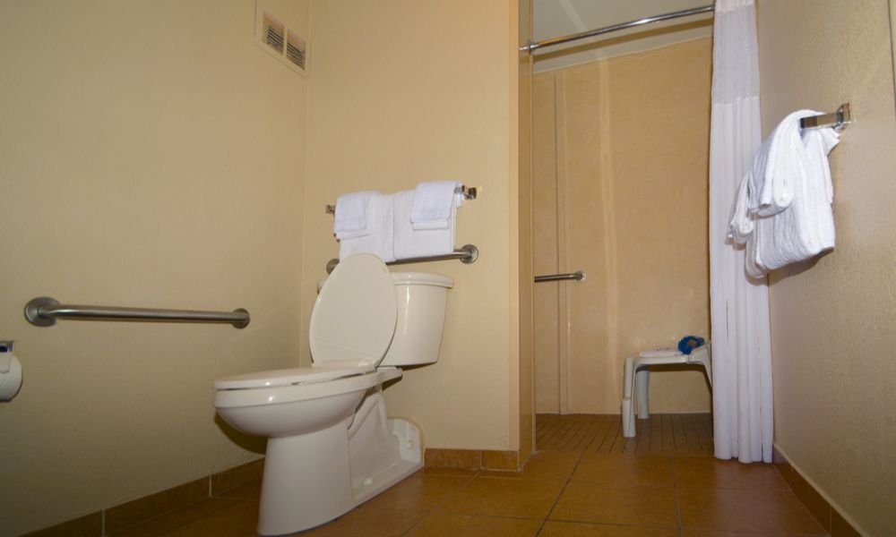 accessible bathroom with grab rails, wheel-in shower and shower chair
