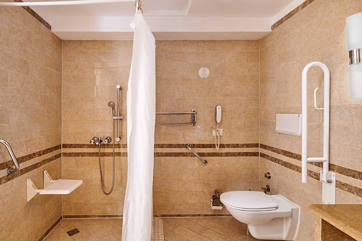 adapted bathroom with a shower chair, wheel-in shower and grab rails